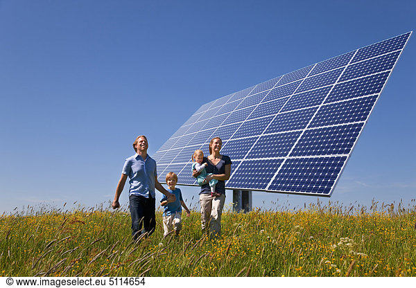 Family walking in field by solar panel