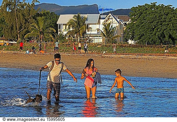 Family walking in Tamarin beach  Mauritius. Relection in the water.