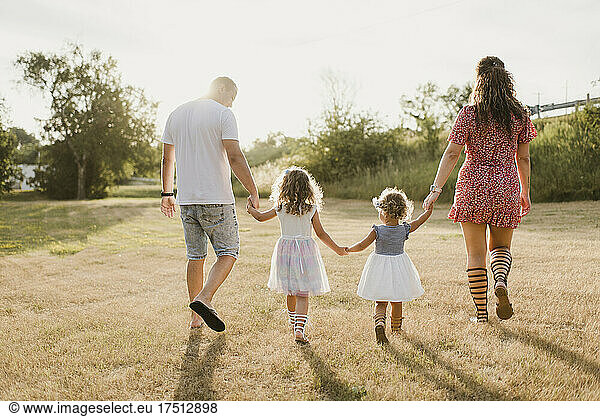 Family walking on a meadow in backlight