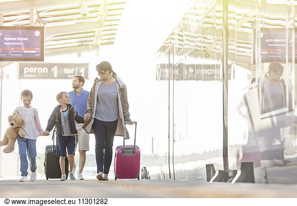 Family walking pulling suitcases in airport concourse