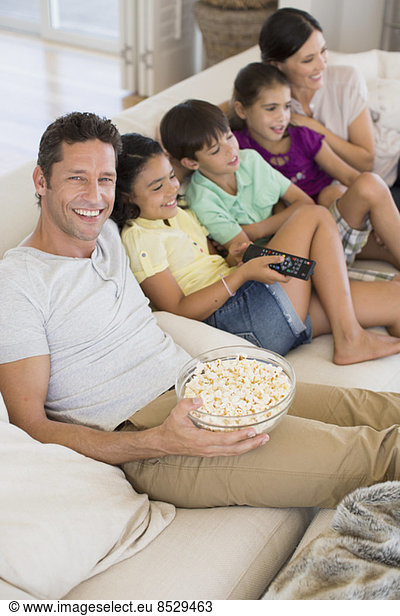 Family watching TV on sofa in living room