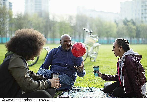 Family with soccer ball and coffee in park grass