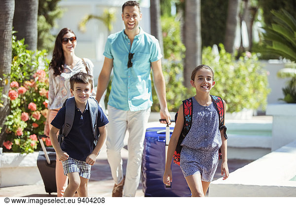 Family with suitcases walking towards tourist resort