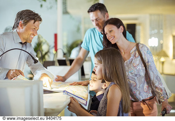 Family with two children at reception desk in hotel lobby