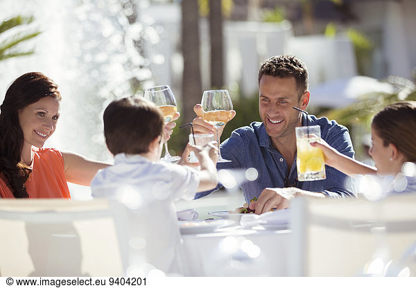 Family with two children raising toast at table outdoors