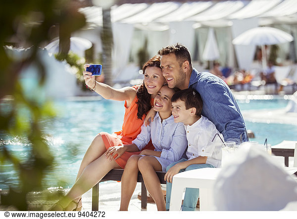 Family with two children taking selfie by resort swimming pool