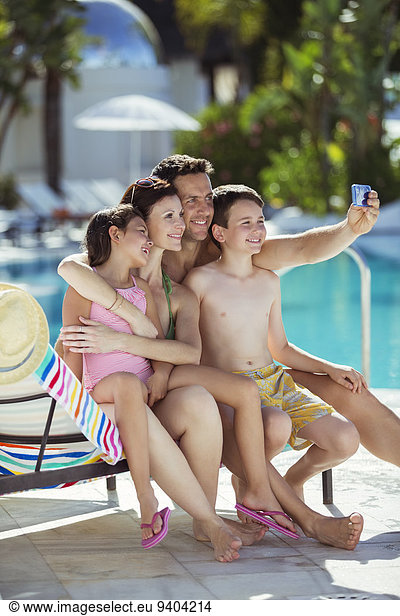 Family with two children taking selfie by swimming pool