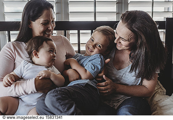 Family with two moms laughing and cuddling at home