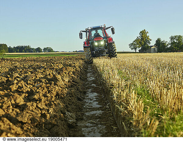 Farmer driving tractor amidst crops in farm
