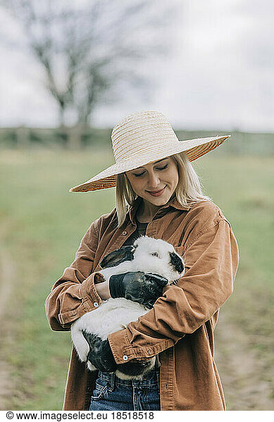 Farmer holding bunny standing in farm