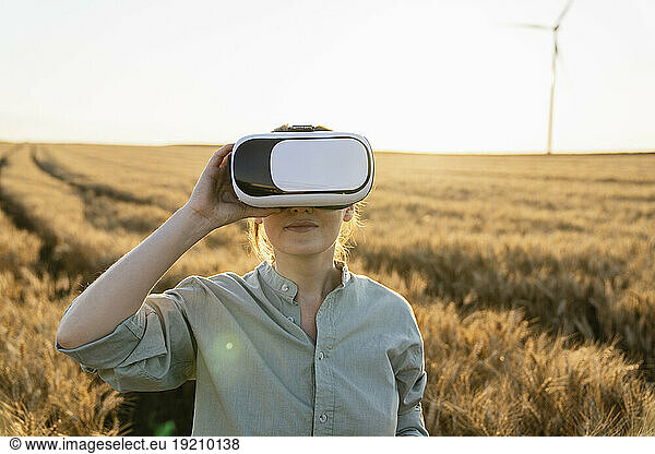 Farmer holding virtual reality headset in wheat field