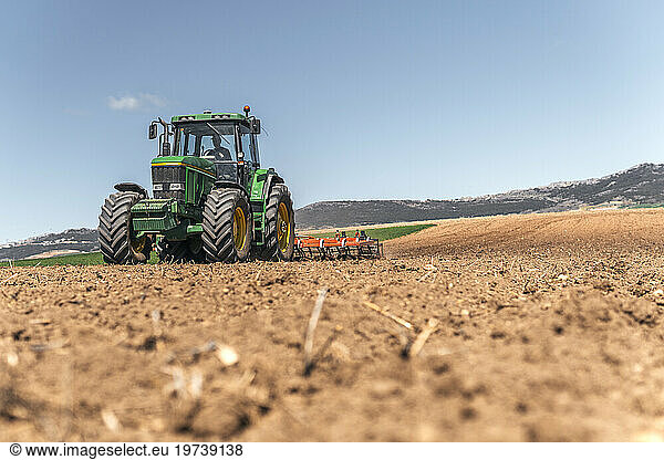 Farmer plowing field with tractor under sky