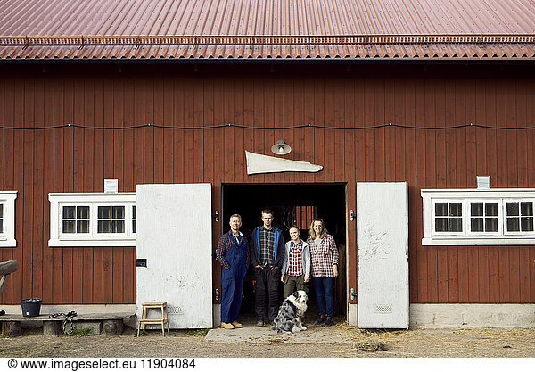 Farmer standing with family at doorway of barn