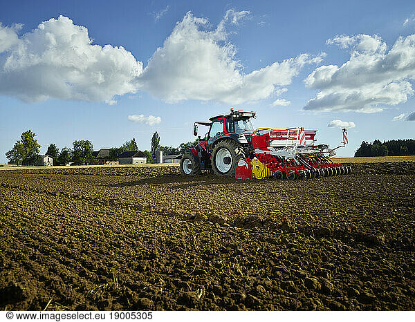 Farmer using tractor in field under sky