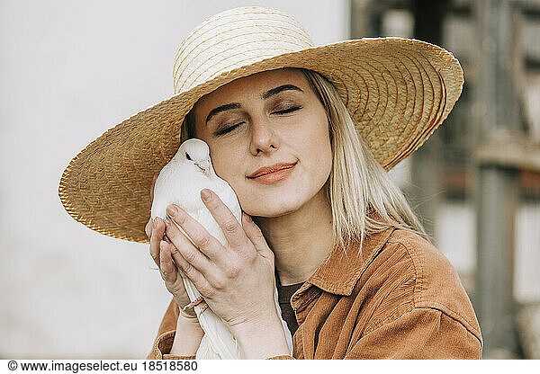 Farmer wearing straw hat holding dove