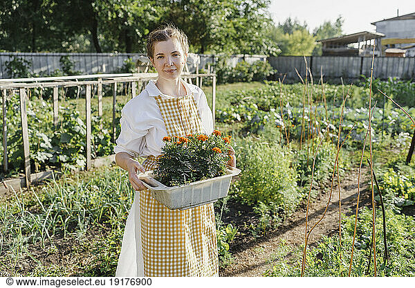 Farmer with flower pot standing in garden