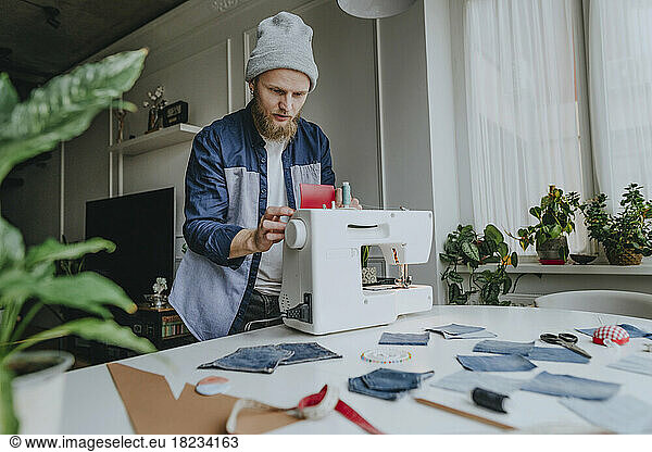 Fashion designer adjusting sewing machine in workshop