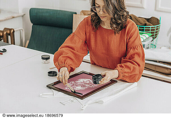 Fashion designer applying ink on fabric at workshop