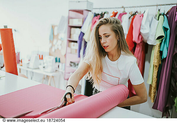 Fashion designer cutting fabric textile in a studio