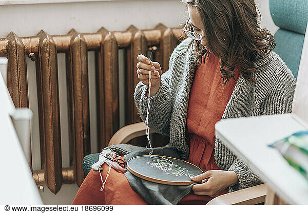 Fashion designer doing embroidery on fabric at workshop