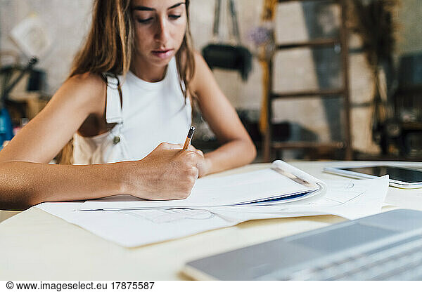 Fashion designer drawing on paper at desk