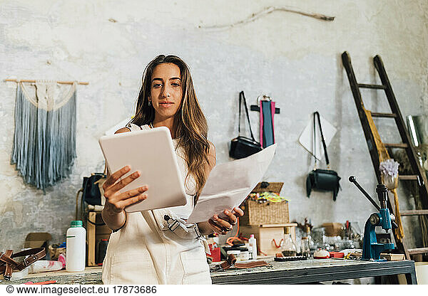 Fashion designer holding paper looking at tablet PC