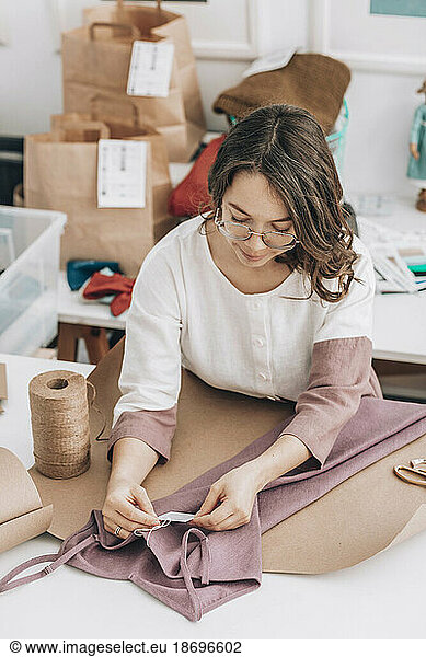 Fashion designer looking at price tag of dress