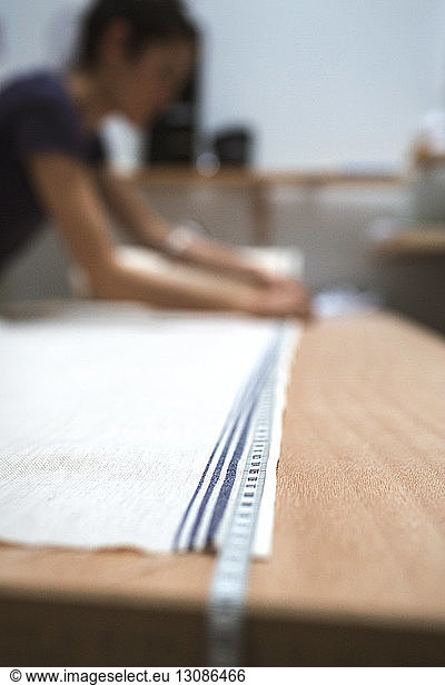 Fashion designer measuring fabric on table in workshop