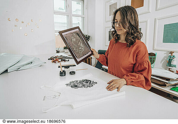 Fashion designer printing design on dress at workshop