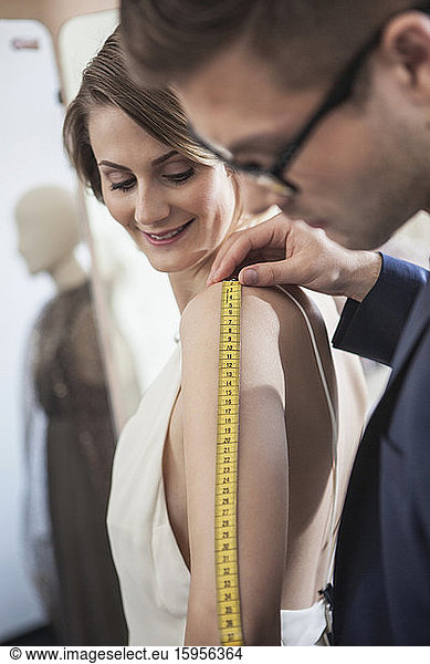 Fashion designer taking measurements of woman