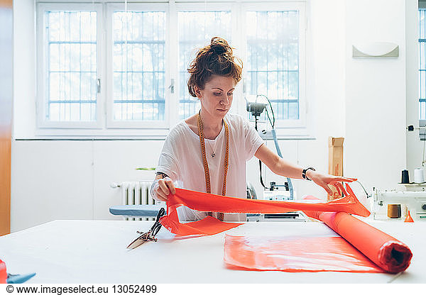 Fashion designer unrolling textile on workbench