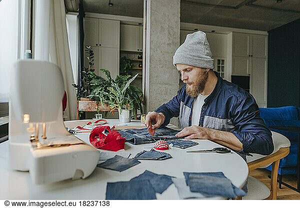 Fashion designer wearing knit hat working on denim bag
