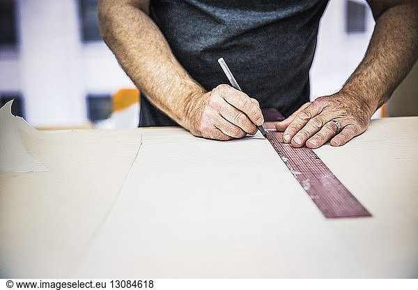Fashion designer working with ruler on fabric swatch at table in design studio
