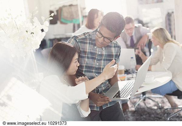 Fashion designers brainstorming with laptop in office