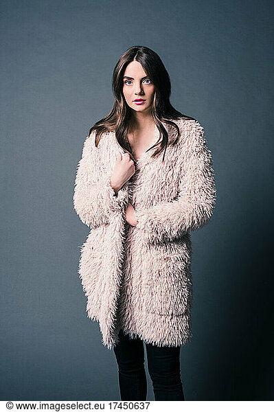Fashion Model Poses with Blush Fur Coat on Gray Background