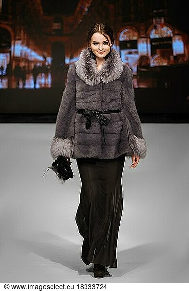 Fashion model walks on runway in fur coat during fashion show