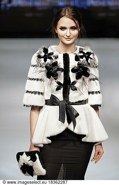 Fashion model walks on runway in fur coat during fashion show