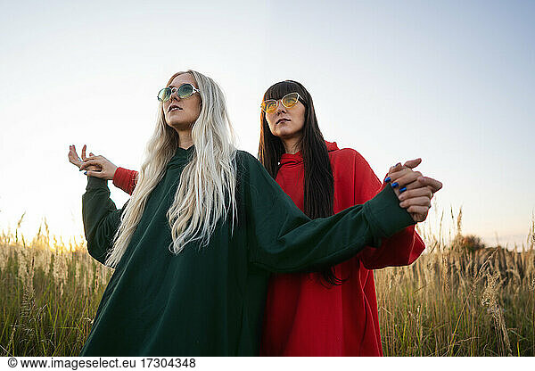 Fashion twin girls posing in bright clothes in the field