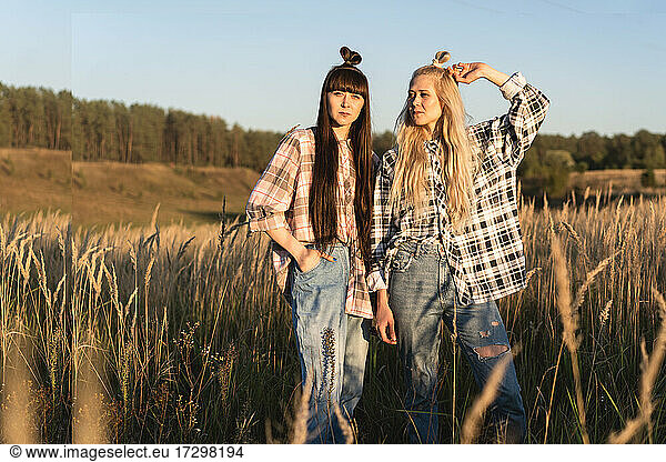 Fashion twin girls posing in jeans clothes in the field
