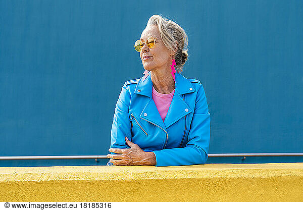 Fashionable mature woman in front of blue wall