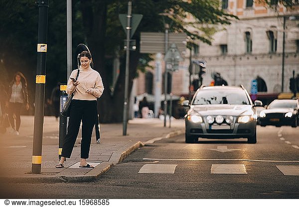 Fashionable woman using mobile phone while standing in city