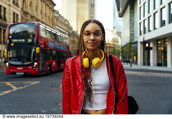 Fashionable young woman with braided hair standing on road in city