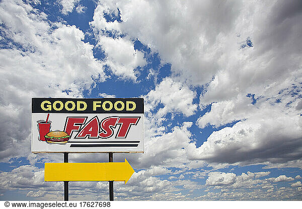 Fast food sign by the road  Good Food Fast and a yellow arrow.