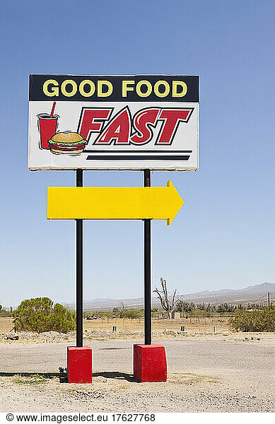Fast food sign by the road  Good Food Fast and a yellow arrow.