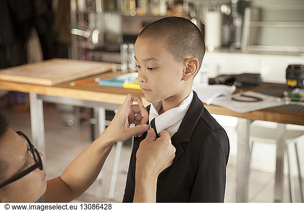 Father adjusting son's necktie at home