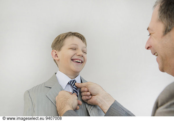 Father adjusting sons tie  smiling
