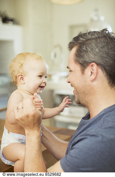 Father and baby laughing in kitchen