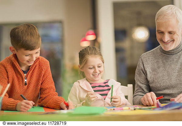Father and children bonding  doing crafts at table