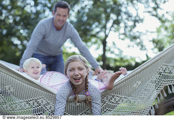 Father and children laying in hammock outdoors