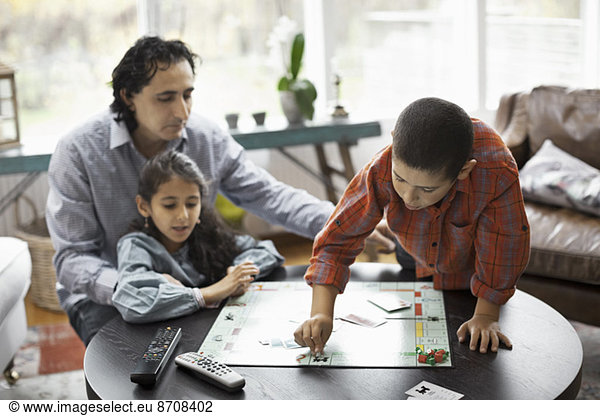 Father and children playing monopoly game in living room